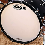 **Bass Drum Foundation:** A low-angle, dynamic shot of a bass drum firmly anchored on a drum rug, its spurs extended for maximum stability. A drummer's foot is precisely positioned on the kick pedal, conveying comfortable and powerful footwork, symbolizing the rhythmic foundation of the kit.